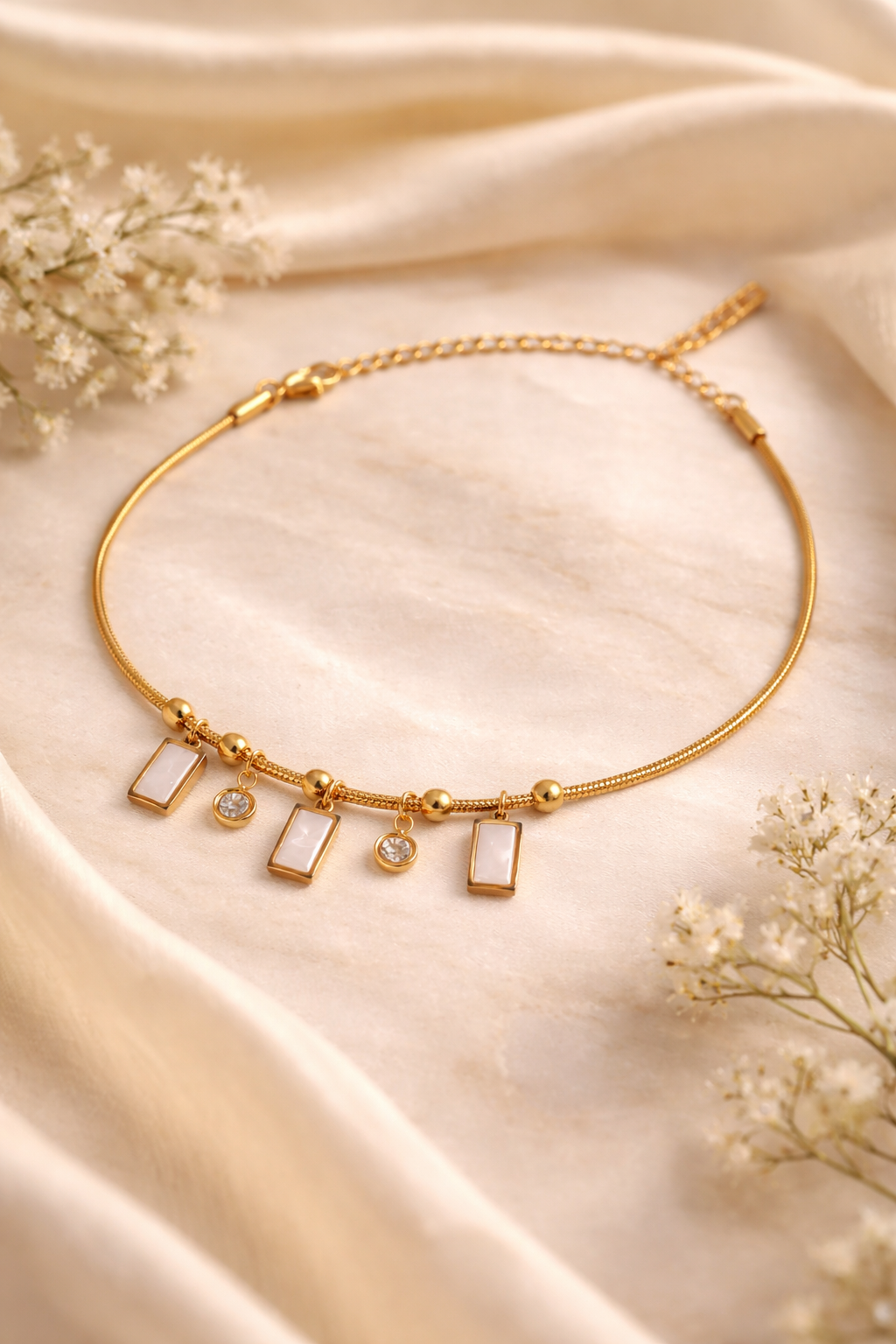 Gold plated charm bracelet by Prifine featuring various decorative charms on a delicate chain.
