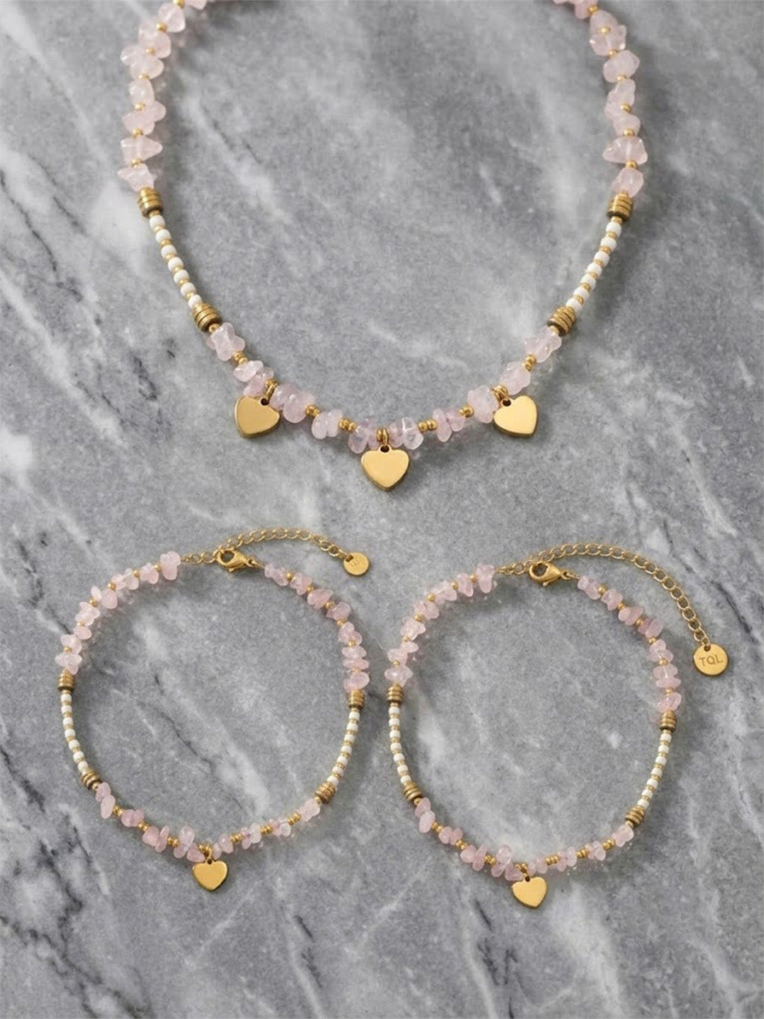 Rose Quartz heart charm jewelry set featuring a gold-plated necklace, bracelet, and earrings with natural stones and anti-tarnish finish.