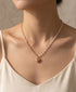 Prifine dainty half pearl and paperclip heart necklace hanging on a display, showcasing its elegant mixed metal design.