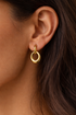 Prifine gold hoop drop earring with sleek, circular design and dangling element on a white background.