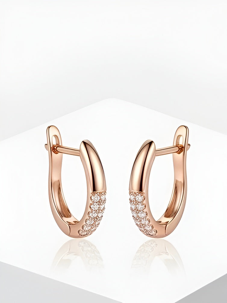Rose gold shimmer hoops earrings by Prifine hanging on a display with a bright background.